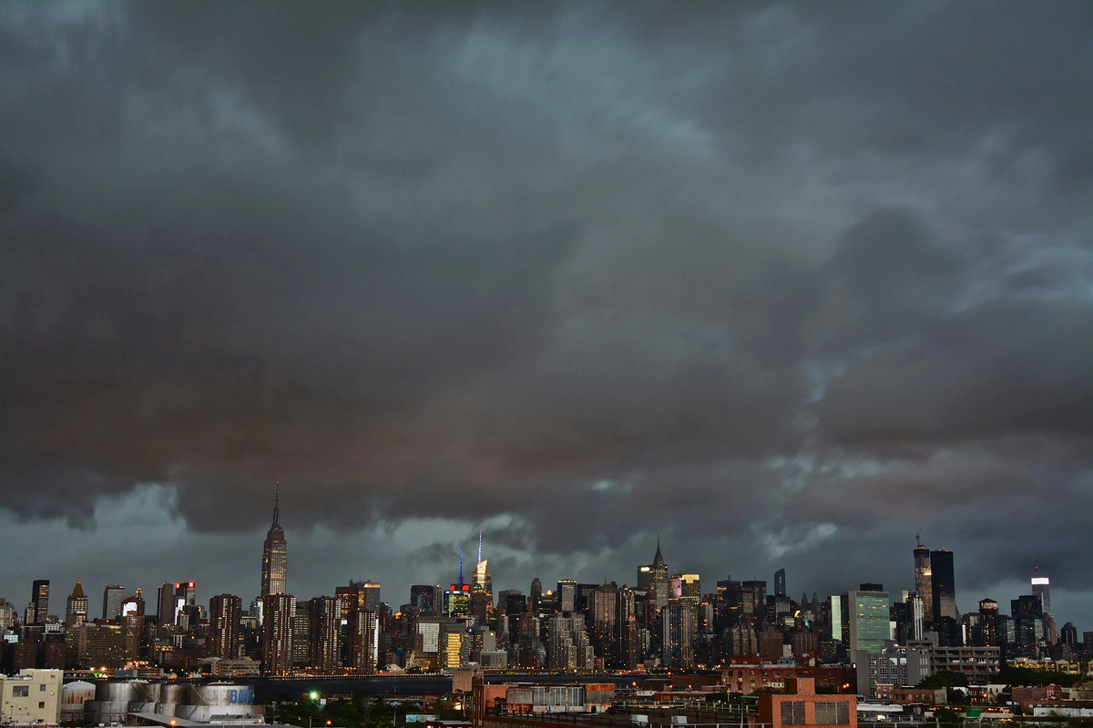 The Manhattan skyline beneath dark storm clouds at dusk.